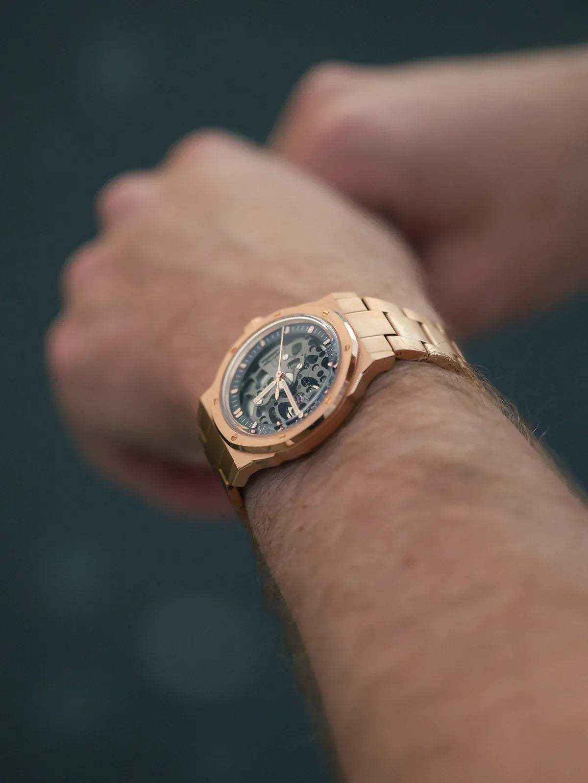 Rose gold watch on a wrist with a blurred background