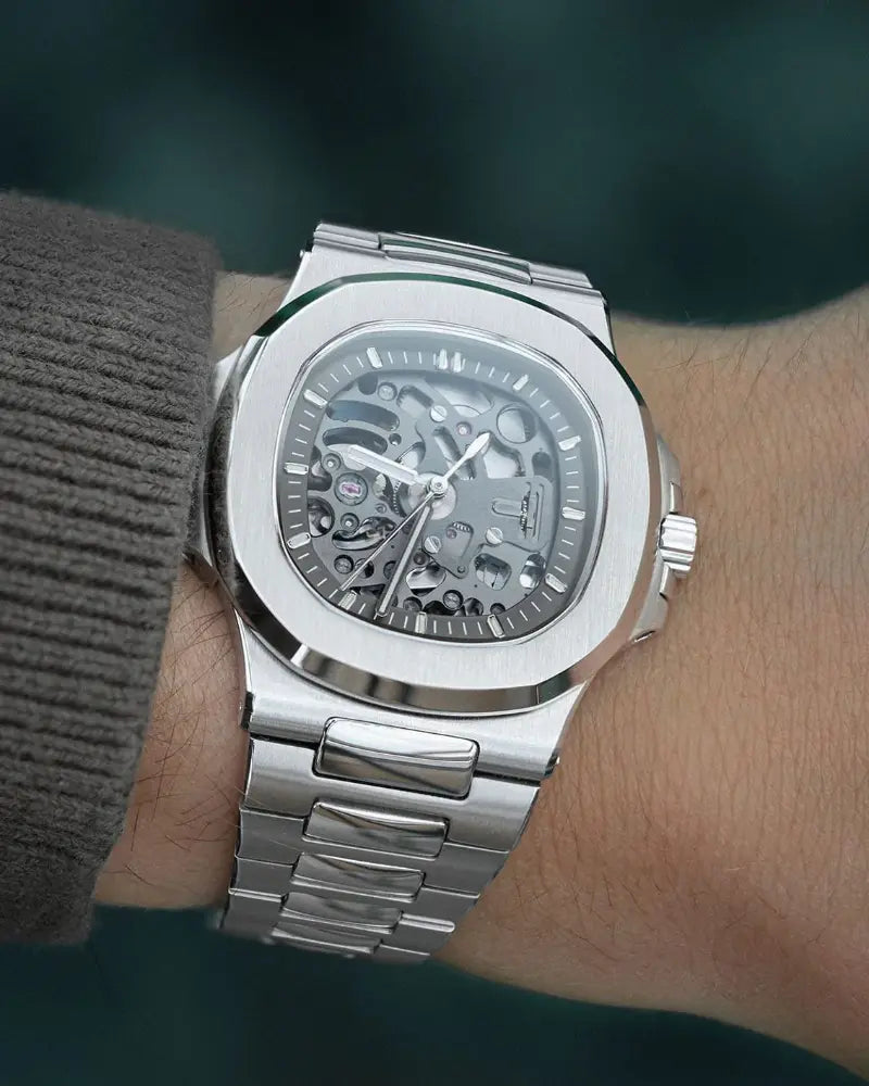 Silver wristwatch with a detailed mechanism on a person's wrist against a dark background
